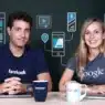 Two people sit at a table with laptops and mugs, both wearing branded shirts—one with Facebook and the other with Google. The background features digital icons, highlighting social media, technology, and opportunities to learn courses online.
