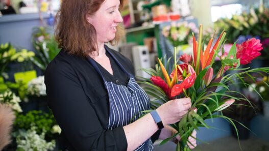 Florist's hands arranging a fresh flower bouquet at a workbench