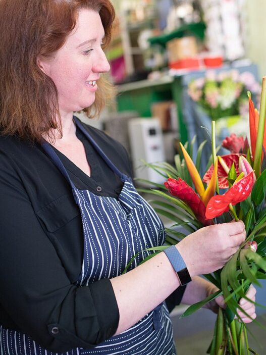 Florist's hands arranging a fresh flower bouquet at a workbench