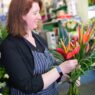 Florist's hands arranging a fresh flower bouquet at a workbench