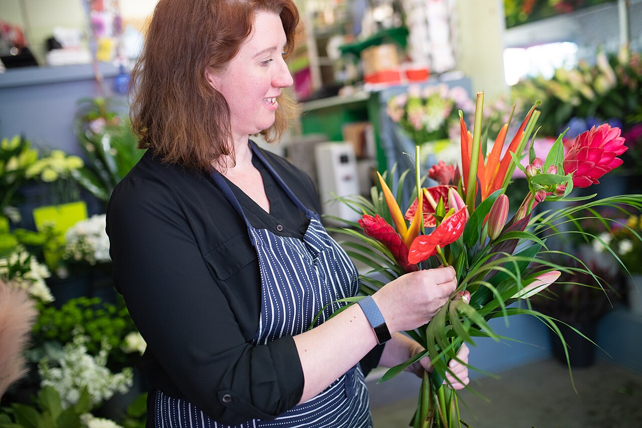 Florist's hands arranging a fresh flower bouquet at a workbench