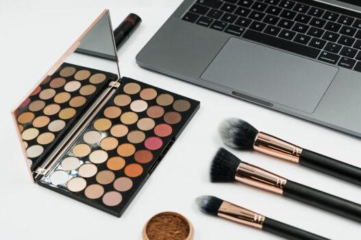 Beauty content creator filming a makeup tutorial with cosmetics and laptop setup