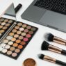 Beauty content creator filming a makeup tutorial with cosmetics and laptop setup