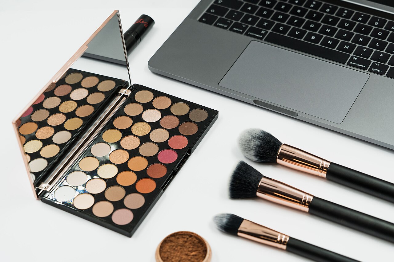 Beauty content creator filming a makeup tutorial with cosmetics and laptop setup