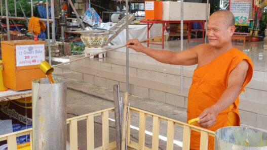 A candlemaker hand-pouring candles at a workbench