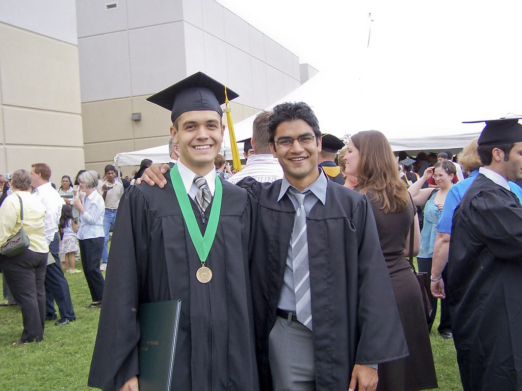 Two graduates in caps and gowns celebrating outdoors