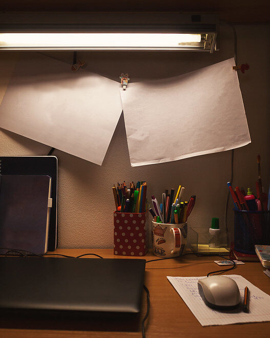 Person studying on a laptop at a small home desk