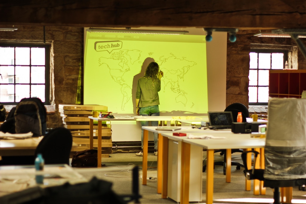 Artist drawing a large world map mural in a studio