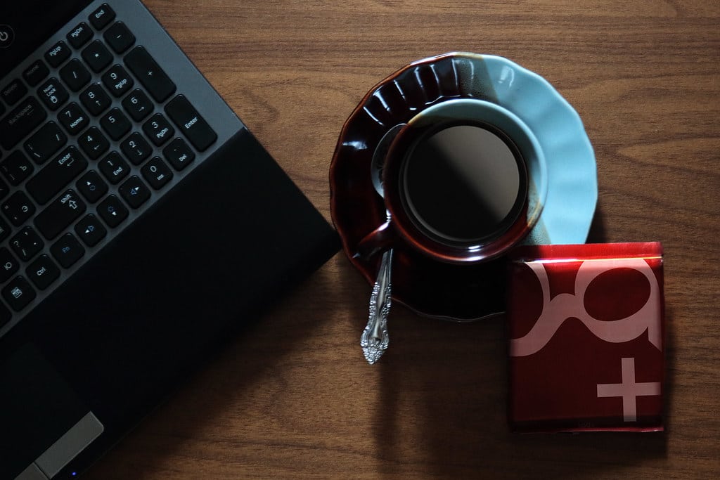Laptop and a cup of coffee on a wooden desk from above