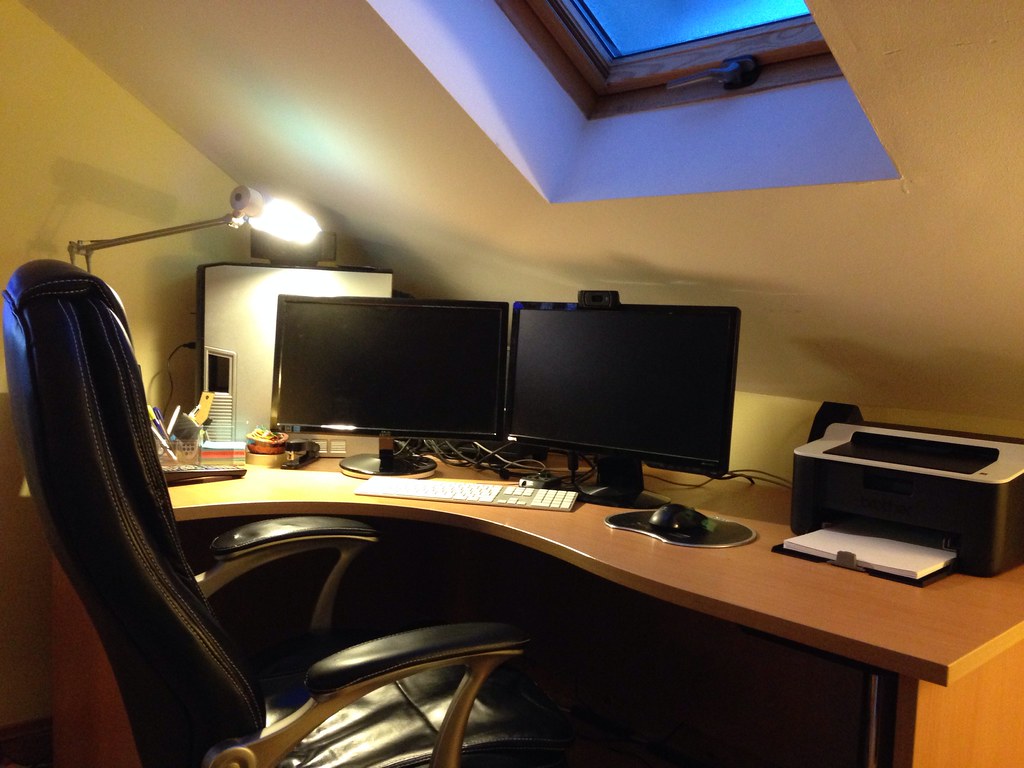 Home office desk with two monitors under a skylight