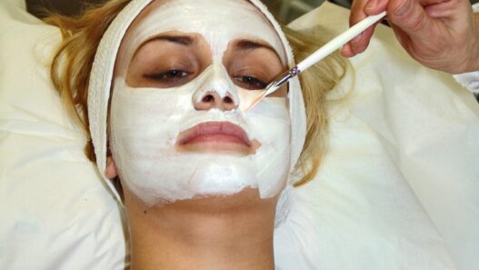 Esthetician applying a facial mask treatment to a client