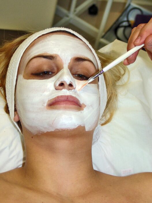 Esthetician applying a facial mask treatment to a client