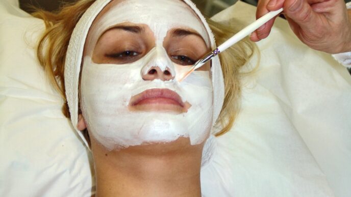 Esthetician applying a facial mask treatment to a client