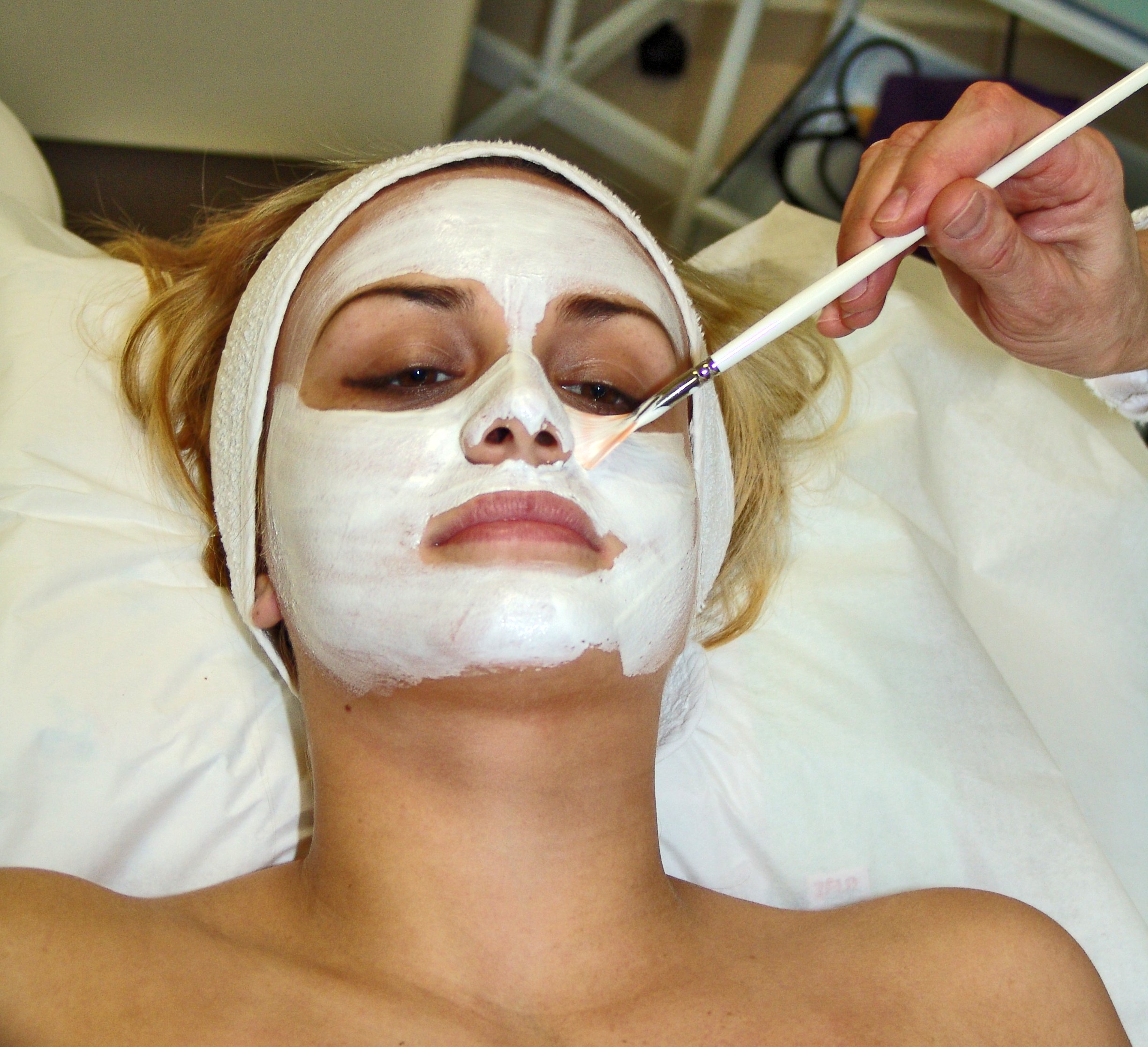 Esthetician applying a facial mask treatment to a client