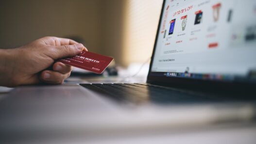 Hand holding a credit card next to a laptop
