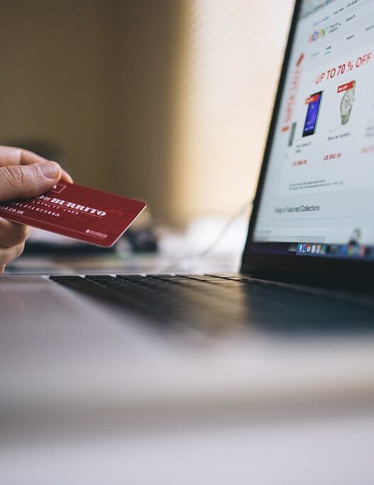 Hand holding a credit card next to a laptop