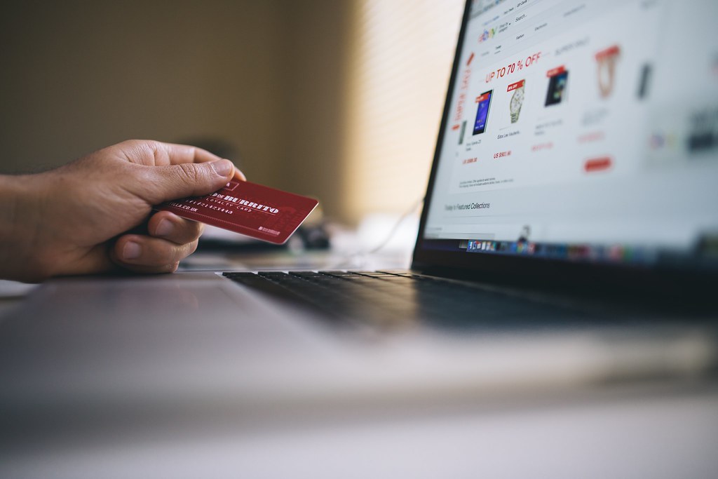 Hand holding a credit card next to a laptop