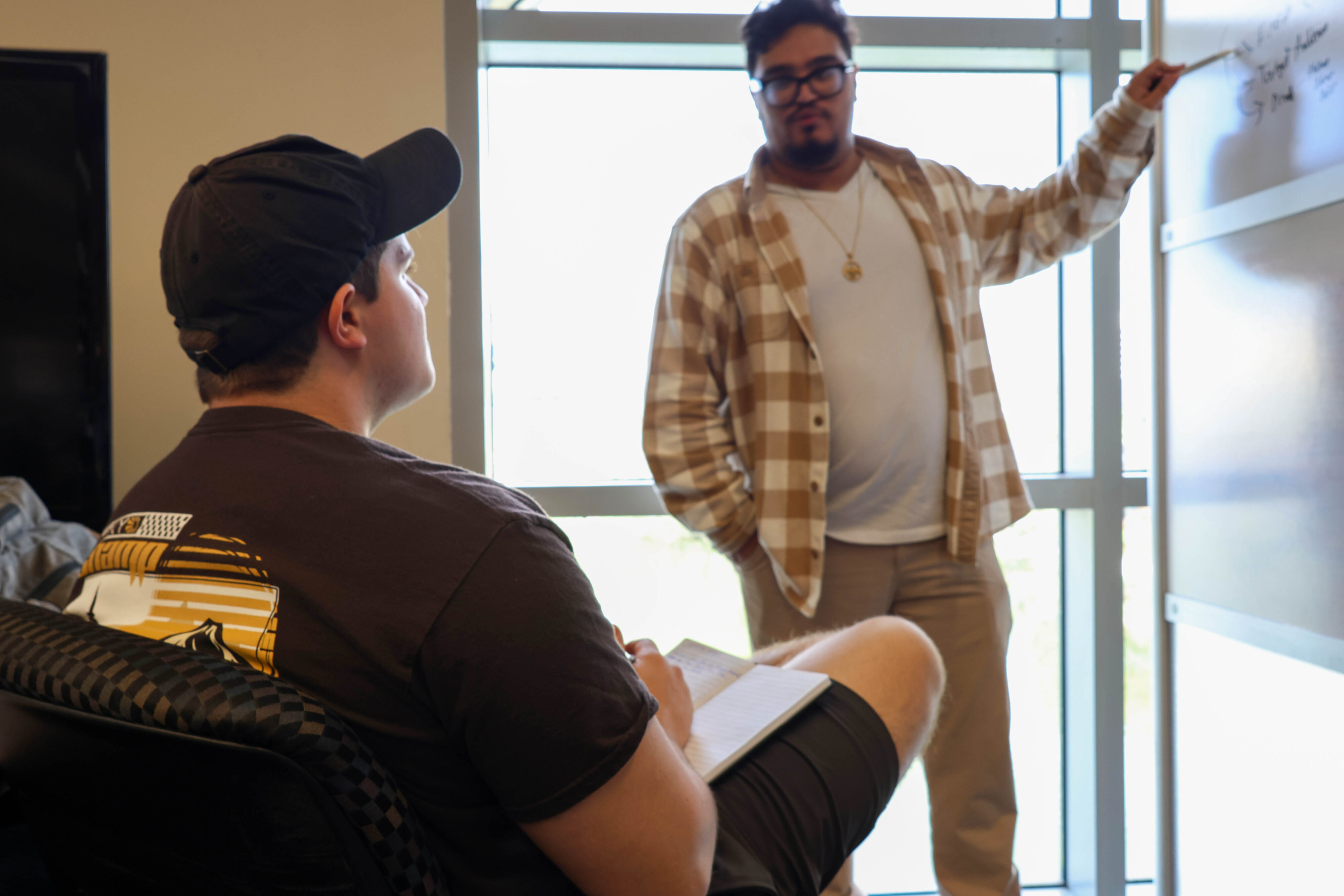 Student taking notes while an instructor explains a concept