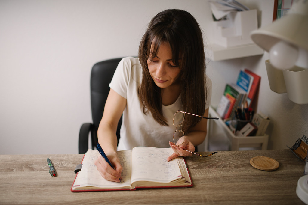 Young woman sitting at a wooden desk writing