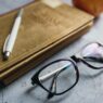 Study materials, glasses, pen and apple on a desk