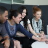 Four students gathered around a laptop learning together