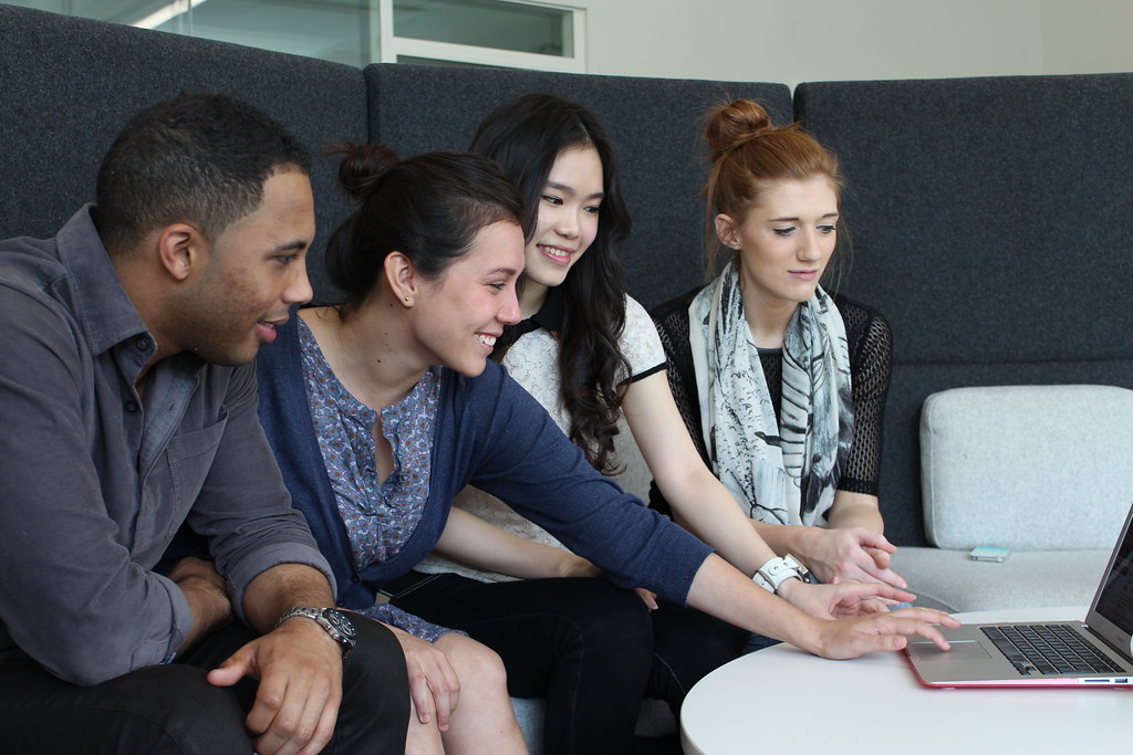 Four students gathered around a laptop learning together
