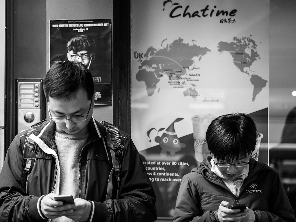 Two people absorbed in their smartphones on the street