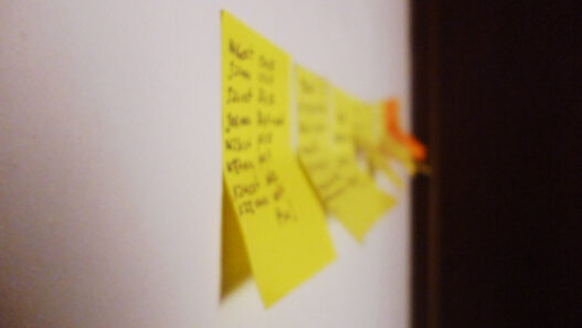 Yellow sticky notes with handwritten tasks on a wall