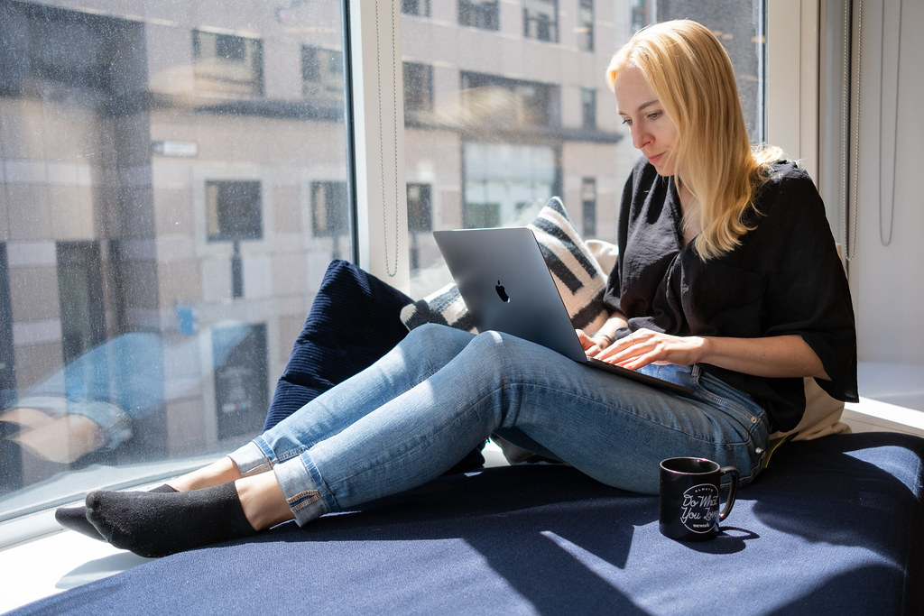 Woman working on a laptop by a sunny window