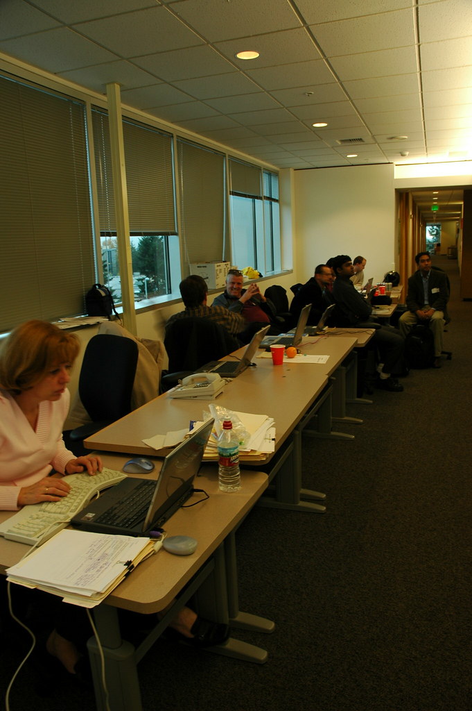 People working on laptops around a long office table
