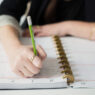 A hand writing in a planner with a pen