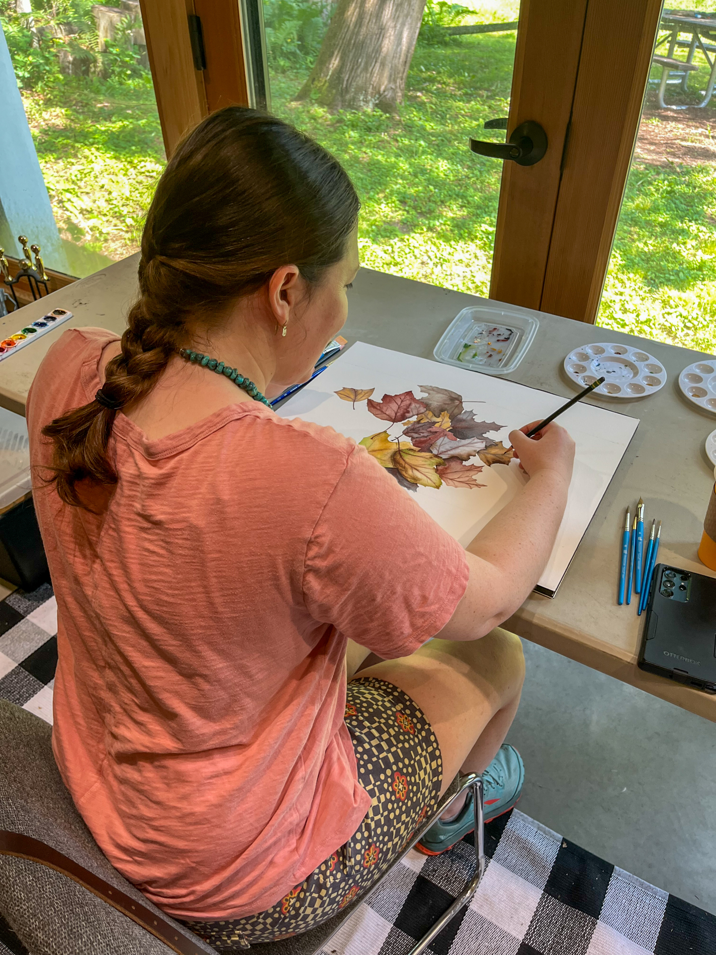 Artist painting watercolor leaves on paper