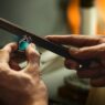Hands filing a metal ring at a jeweler's workbench