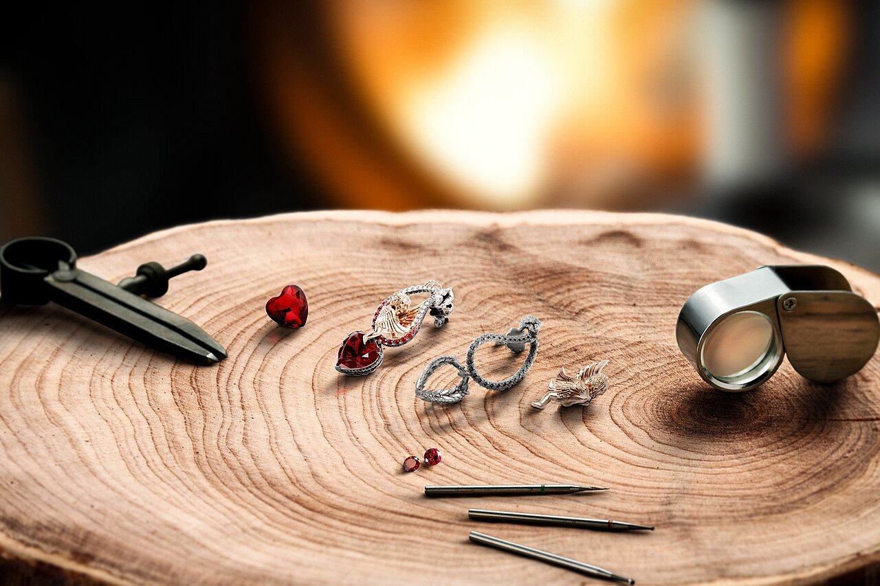 Jewelry making tools, gemstones and finished pieces on a bench