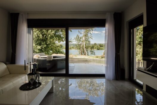 Modern living room with large windows showing view of trees and lake
