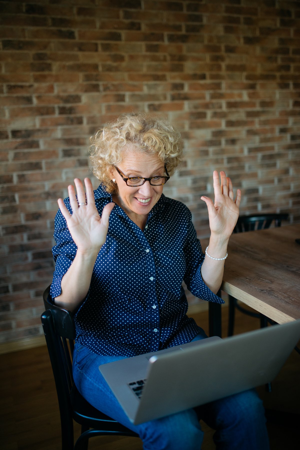 Woman smiling on a video call on her laptop, gesturing happily