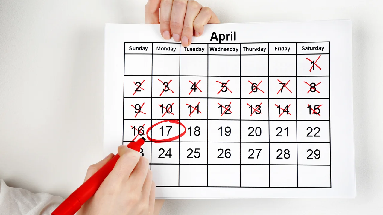 Woman marking date in calendar on white wall background