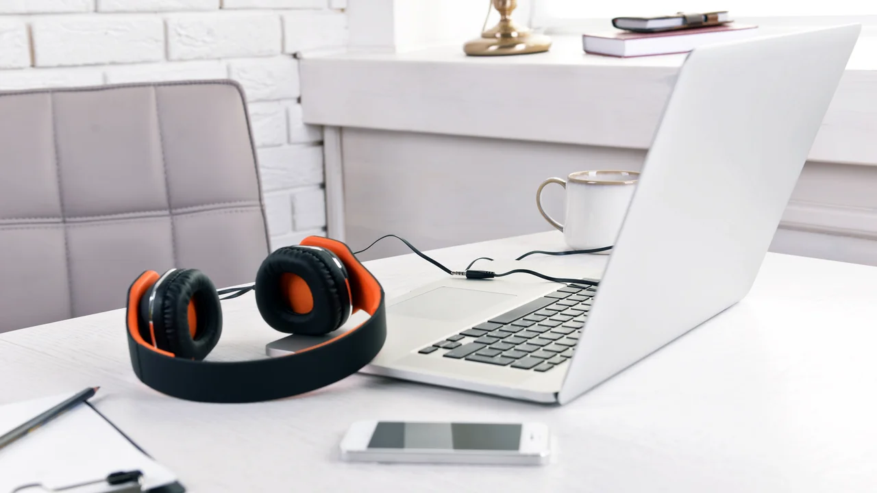 Headphones and other devices on wooden desktop in office
