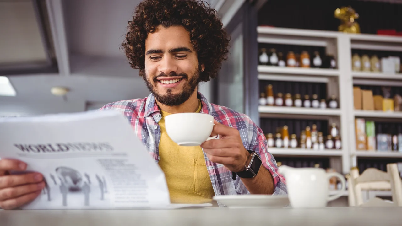 Man reading newspaper while having coffee