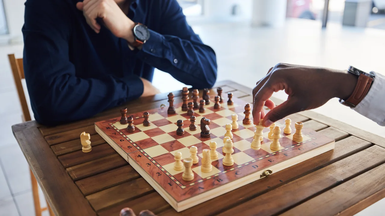 Hands competition and people with a chess game strategy and playing together for fun table professional and friends with a board for gaming learning and expert with a skill or hobby in a room