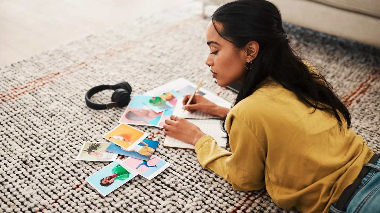 I need to pick out the best picture cropped shot of an attractive young businesswoman lying on her living room floor and sorting through polaroids for her blog