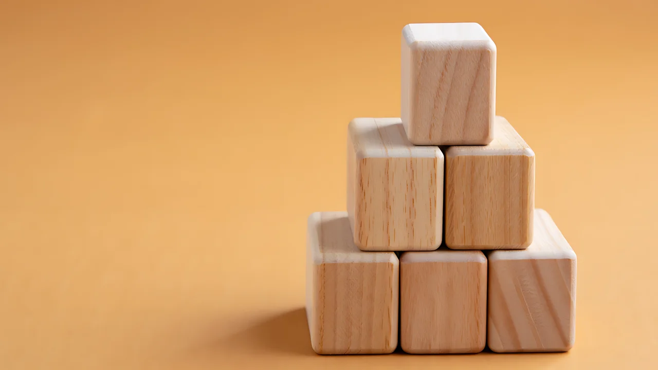 Stack of natural wooden building blocks arranged in a pyramid shape on a warm orange background