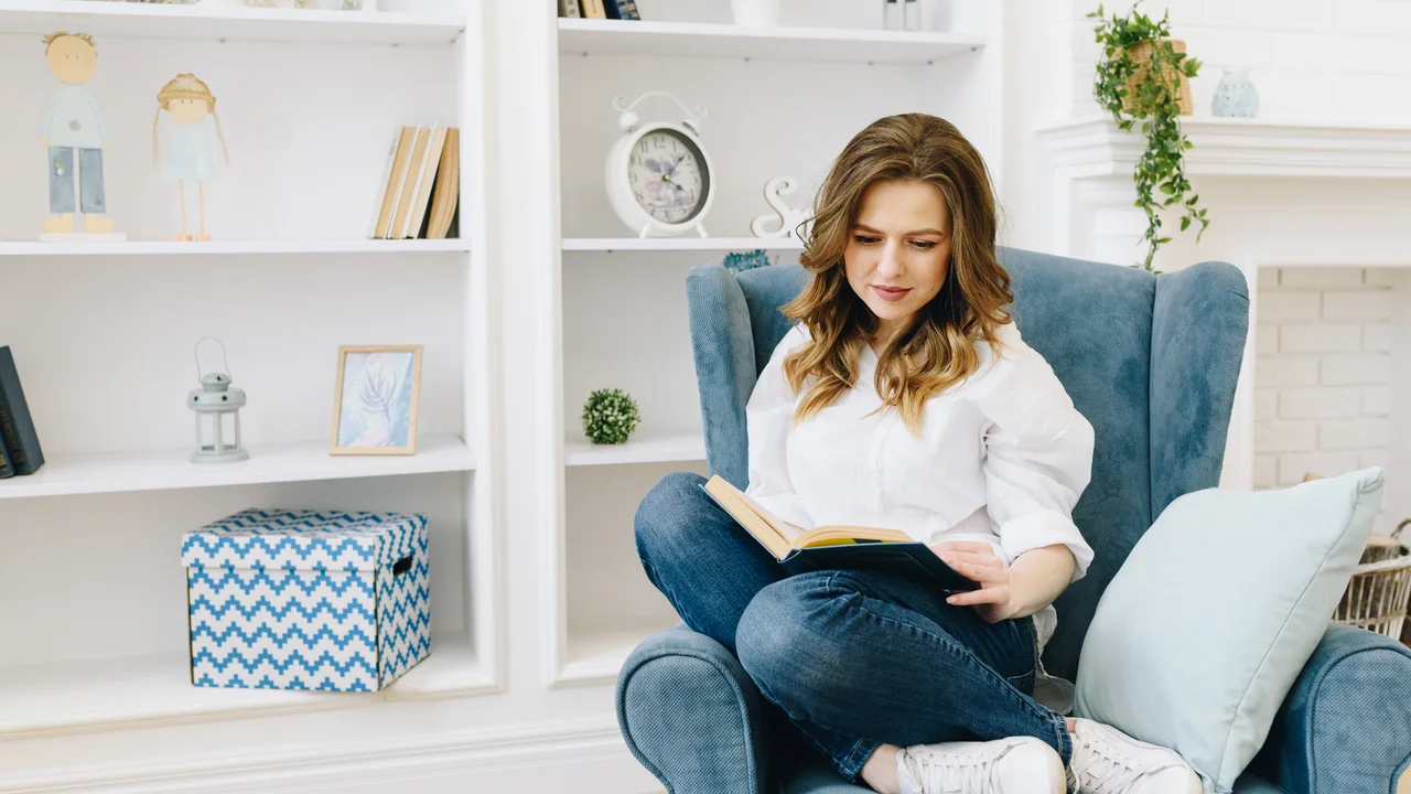 Smart young caucasian woman reading a book in a room